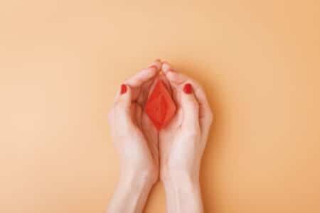 A Red Paper Boat Protectively Covered by a Woman's Hands Signifying HIFU Vaginal Tightening